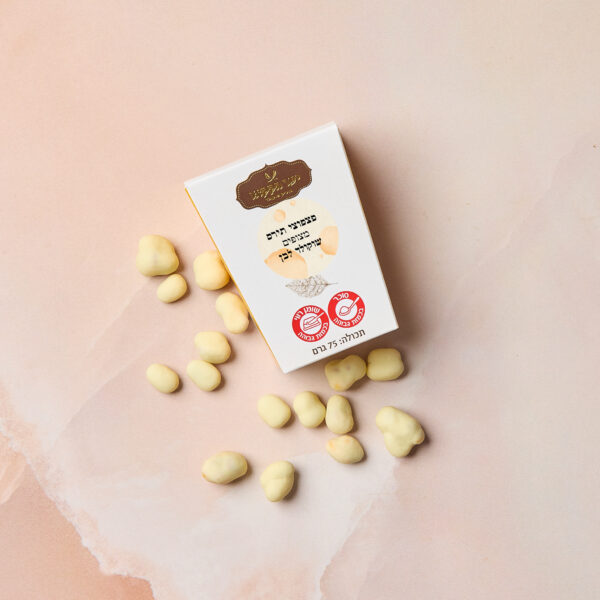 קופסה לבנה עם הכיתוב IMG_2094 בעברית מונחת על משטח ורוד בהיר, מוקפת בקריספי תירס מצופה בשוקולד לבן חלק.