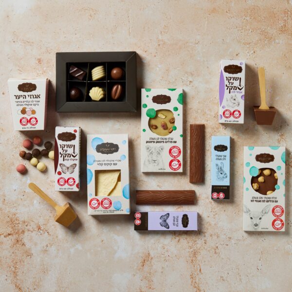 מבחר שמחת הלב מוצג באלגנטיות על משטח בעל מרקם, הכולל קופסאות של שוקולדים, חטיפי שוקולד ושוקולד על מקלות. האריזה מציגה עיצובים מגוונים עם טקסט בעברית.