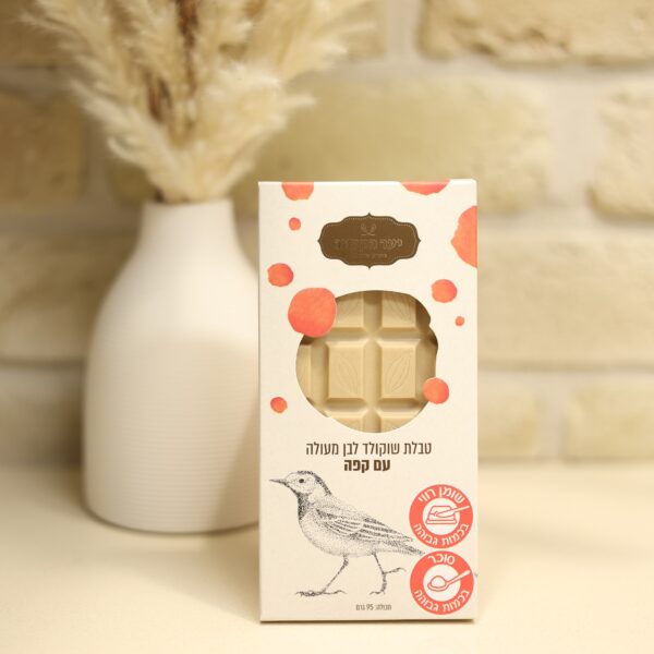 קופסת שוקולד לבן 3I0A2907 בטעם קפה, עם הכיתוב "פולי קפה", גזרת שוקולד, נקודות אדומות בצבעי מים ואיור של ציפור. הקופסה מונחת על משטח בהיר ומאחוריה אגרטל לבן של צמחים מיובשים.