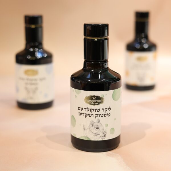 שלושה בקבוקי זכוכית כהים מוצגים על רקע בז' רך. הבקבוק הקדמי מציג תווית מאוירת עם טקסט בכתב שאינו לטיני וציור של חיה, המציע טעמים אקזוטיים כמו ליקר פיסטוק. שני הבקבוקים ברקע מעט לא ממוקדים.